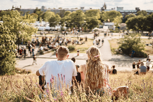 Paar sitzt auf einer Wiese im Mauerpark mit Blick über den Park