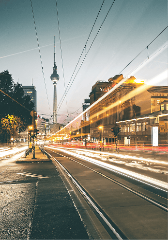 Belebte Straße bei Nacht mit Berliner Fernsehturm und Lichtspuren