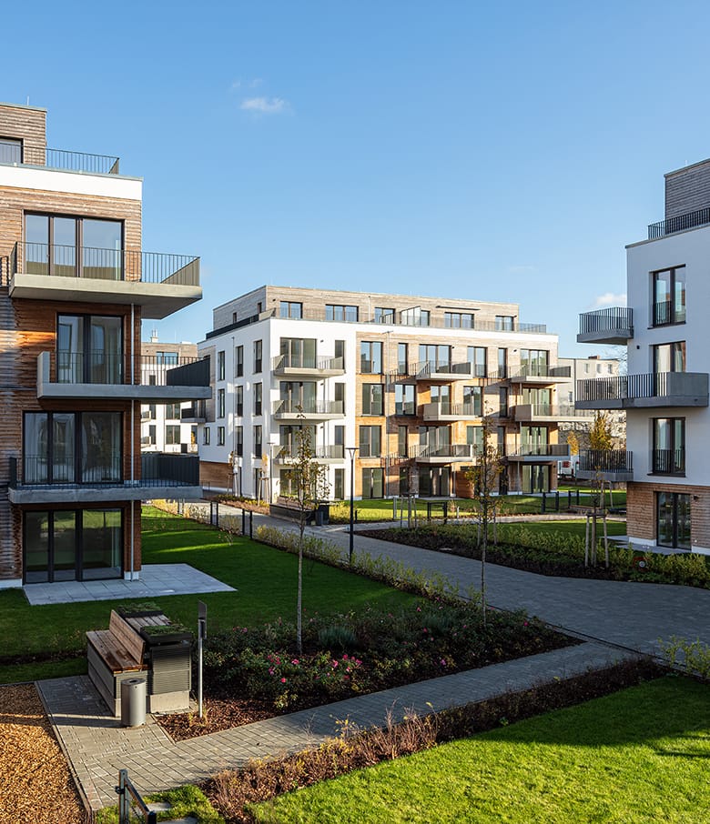 Moderne Wohngebäude mit Klinker- und Holzfassaden, Gartenweg und Bank im Innenhof