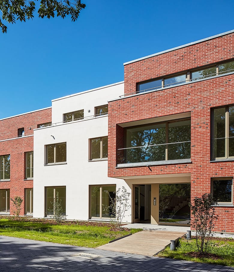 Neubau mit rot verklinkerter und weiß verputzter Fassade unter blauem Himmel