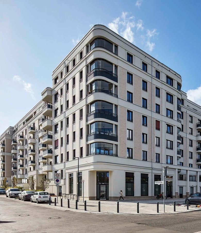 Repräsentatives helles Eckwohnhaus mit Balkonen und geparkten Autos an der Straße