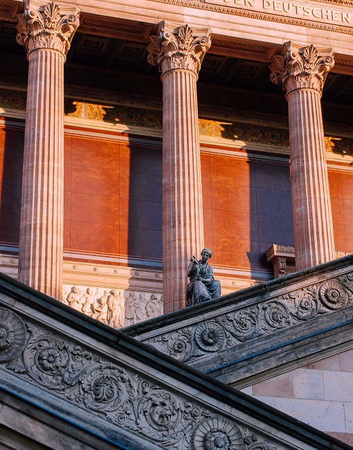 Korinthische Säulen, Statue und verzierte Freitreppe eines klassizistischen Museums im Abendlicht