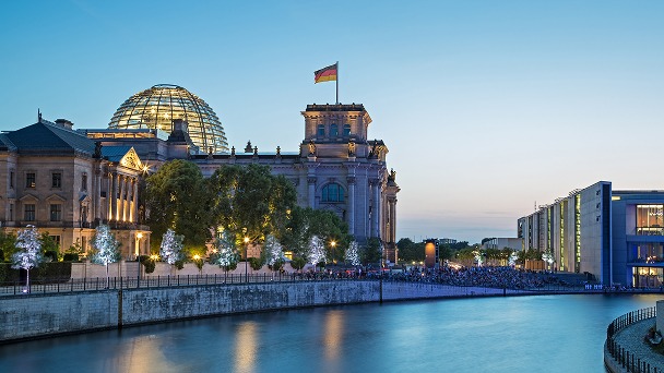 Beleuchtetes Reichstagsgebäude mit Kuppel an der Spree in der Abenddämmerung