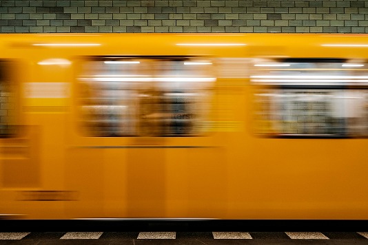 Gelbe U-Bahn fährt mit Bewegungsunschärfe an einem gefliesten Bahnsteig vorbei