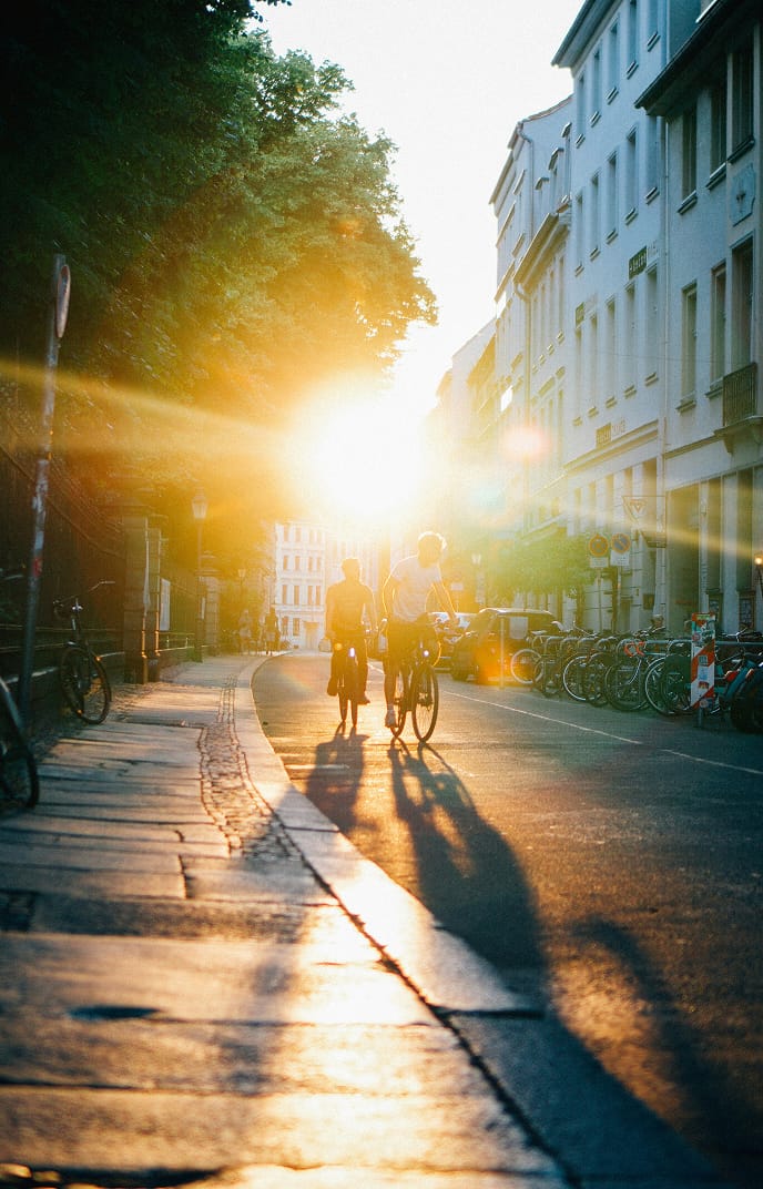 Zwei Radfahrer auf einer Berliner Kopfsteinpflasterstraße im Gegenlicht der Abendsonne