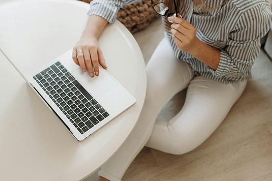 Frau sitzt mit Laptop an einem runden weissen Tisch, Aufnahme von oben