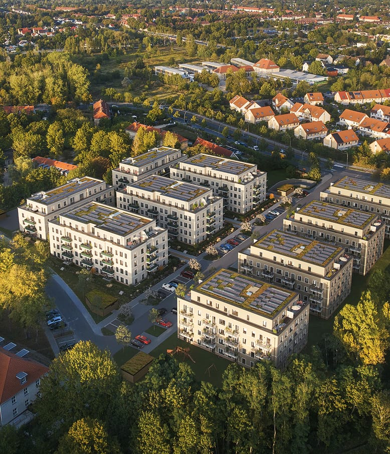 Luftbild-Visualisierung eines Wohnquartiers mit begrünten Dächern, umgeben von Bäumen