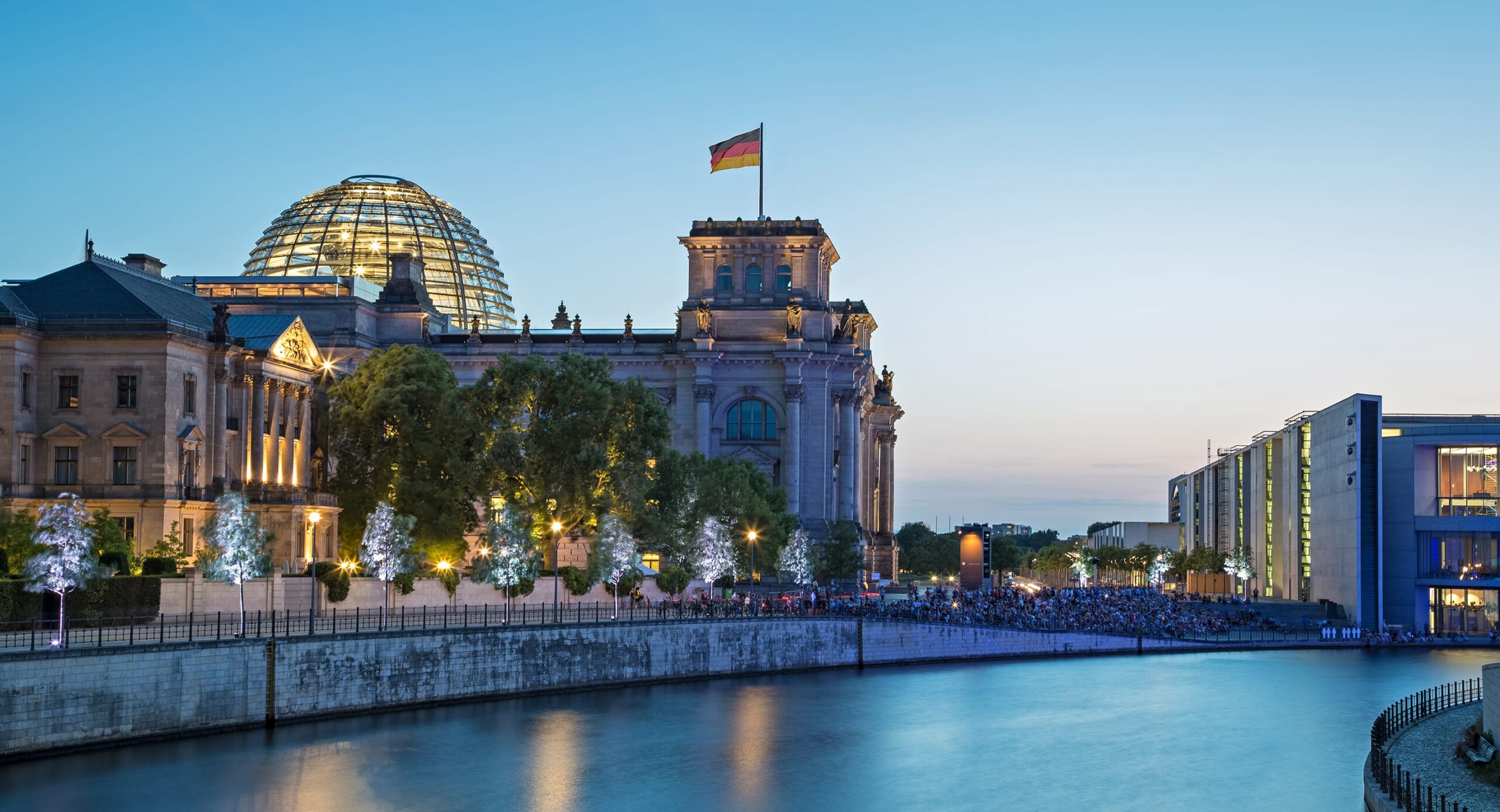 Beleuchtetes Reichstagsgebäude mit Glaskuppel an der Spree in der Abenddämmerung