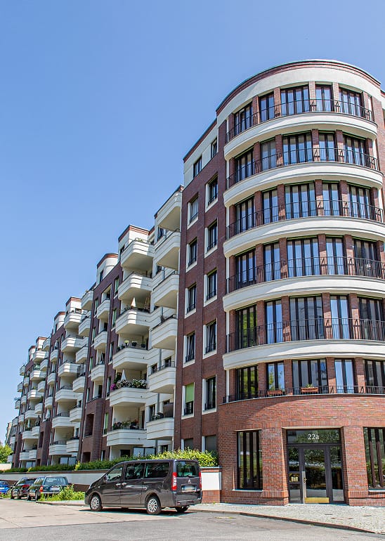 Mehrgeschossiges Wohngebaeude mit gerundeter Klinkerfassade, Balkonen und blauem Himmel