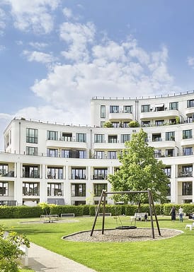 Weisses Wohnensemble mit begruentem Innenhof, Schaukel und Rasenflaeche