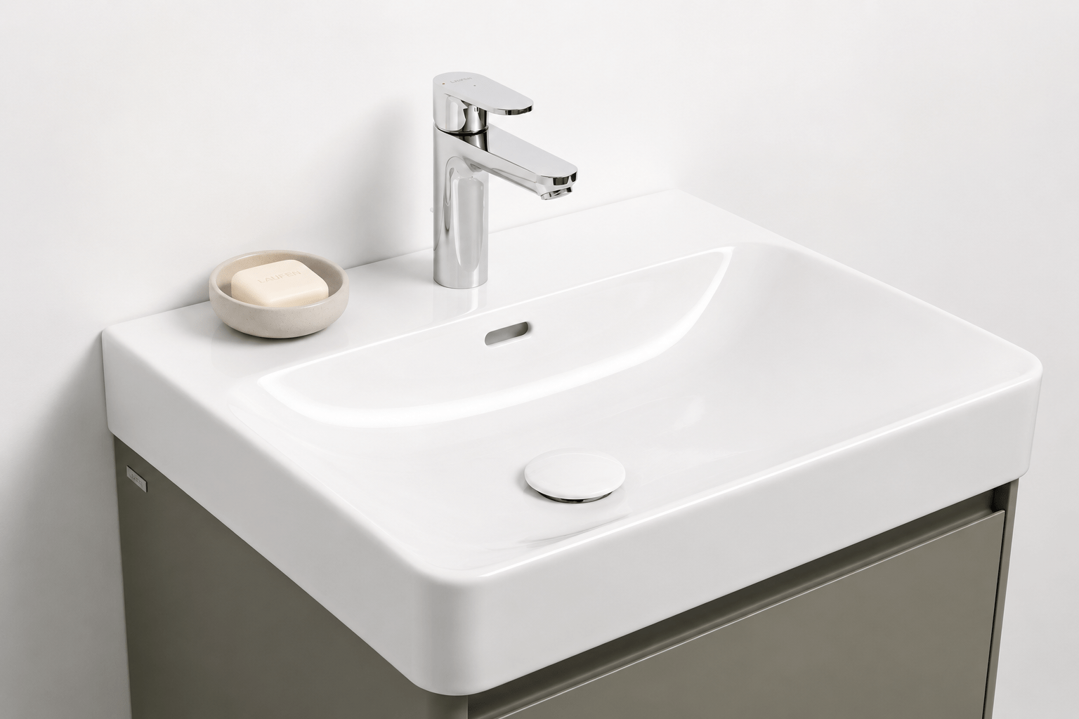 Eckiges weißes Waschbecken mit schlanker Chromarmatur und Seifenschale auf grauem Unterschrank