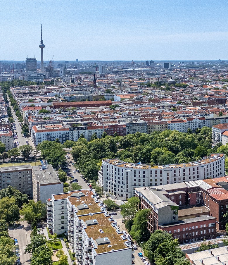 Luftaufnahme des Wohnquartiers mit begruenten Daechern und Berliner Fernsehturm im Hintergrund